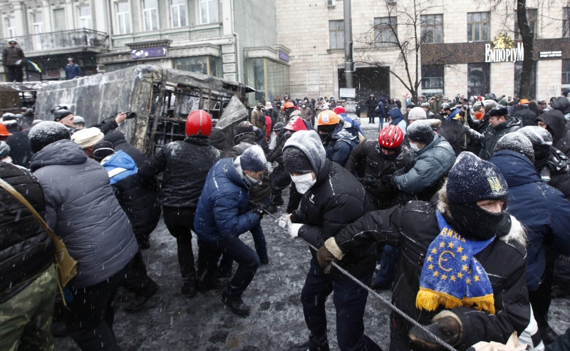 Multidão puxa a carcaça de um veículo queimado durante protesto ontem no centro de Kiev, capital ucraniana | Vasily Fedosenko/Reuters
