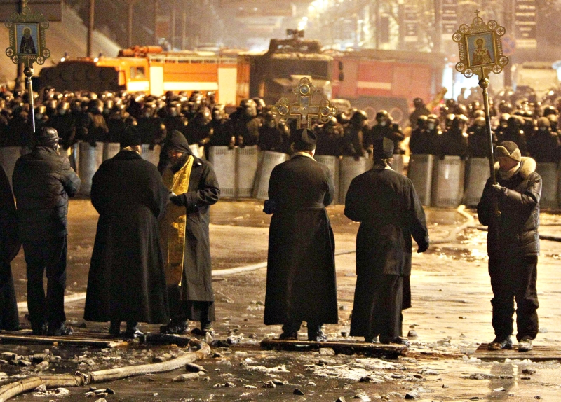 Padres ortodoxos visitam o local dos embates entre civis e a polícia, nos arredores da Praça da Independência | Gleb Garanich/Reuters
