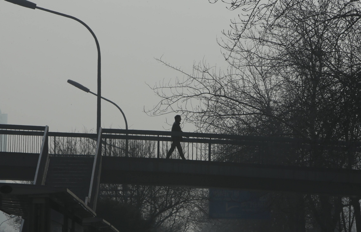 Homem caminha em passarela em meio à névoa densa em Pequim, na China | Reuters/Jason Lee