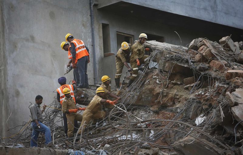 Homens buscam sobreviventes no local onde um prédio desabou neste sábado (4), na Índia | REUTERS/Danish Siddiqui