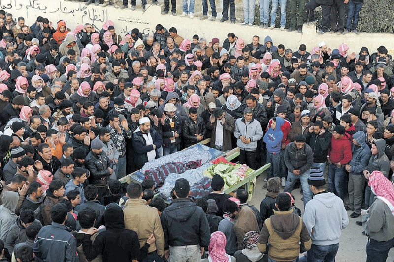 Libaneses rezam ao lado dos corpos de vítimas de um ataque sírio na cidade de Arsal | Hassan Abdallah/Reuters