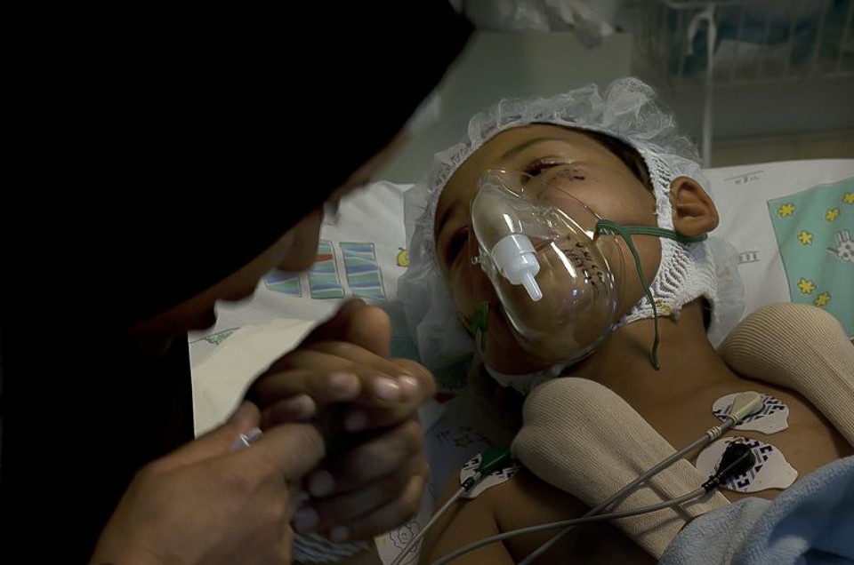Mãe síria e filho que sobreviveram à explosão de um foguete e, abaixo, com uma assistente social em um hospital em Israel | Fotos de Rrina Castelnuovo para The New York Times
