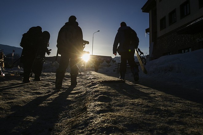 Snowboarders chegam ao alto da montanha no fim da tarde prontos para mais uma descida |