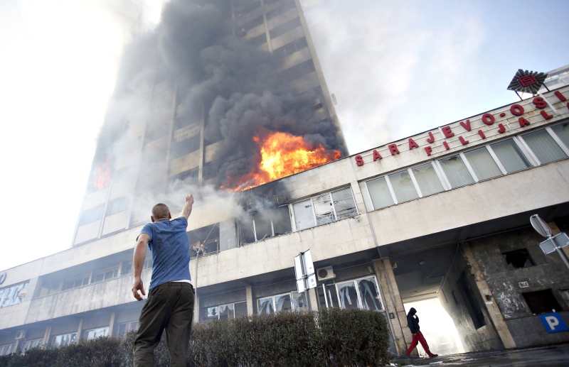 Homem aponta para as chamas no prédio do governo em Tuzla; manifestantes atearam fogo no local e enfrentaram tropas de choque da polícia | Dado Ruvic/Reuters