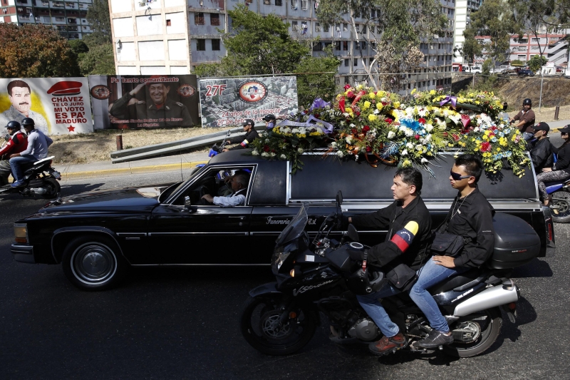 Cortejo fúnebre de Juan Juancho Montoya, uma das três pessoas que morreram nos protestos, passa por imagens de Hugo Chávez e Nicolás Maduro | Carlos Garcia Rawlins/Reuters