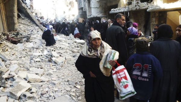 Mulher síria recebe ração alimentar no campo de refugiados de al-Yarmouk, ao sul de Damasco | Mohamad Mohamad/Reuters