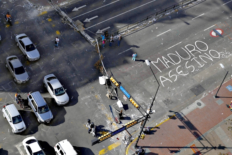 Manifestantes bloqueiam uma rua em Caracas. No asfalto, perto da Praça Altamira, está escrito: Maduro assassino | Jorge Silva/Reuters