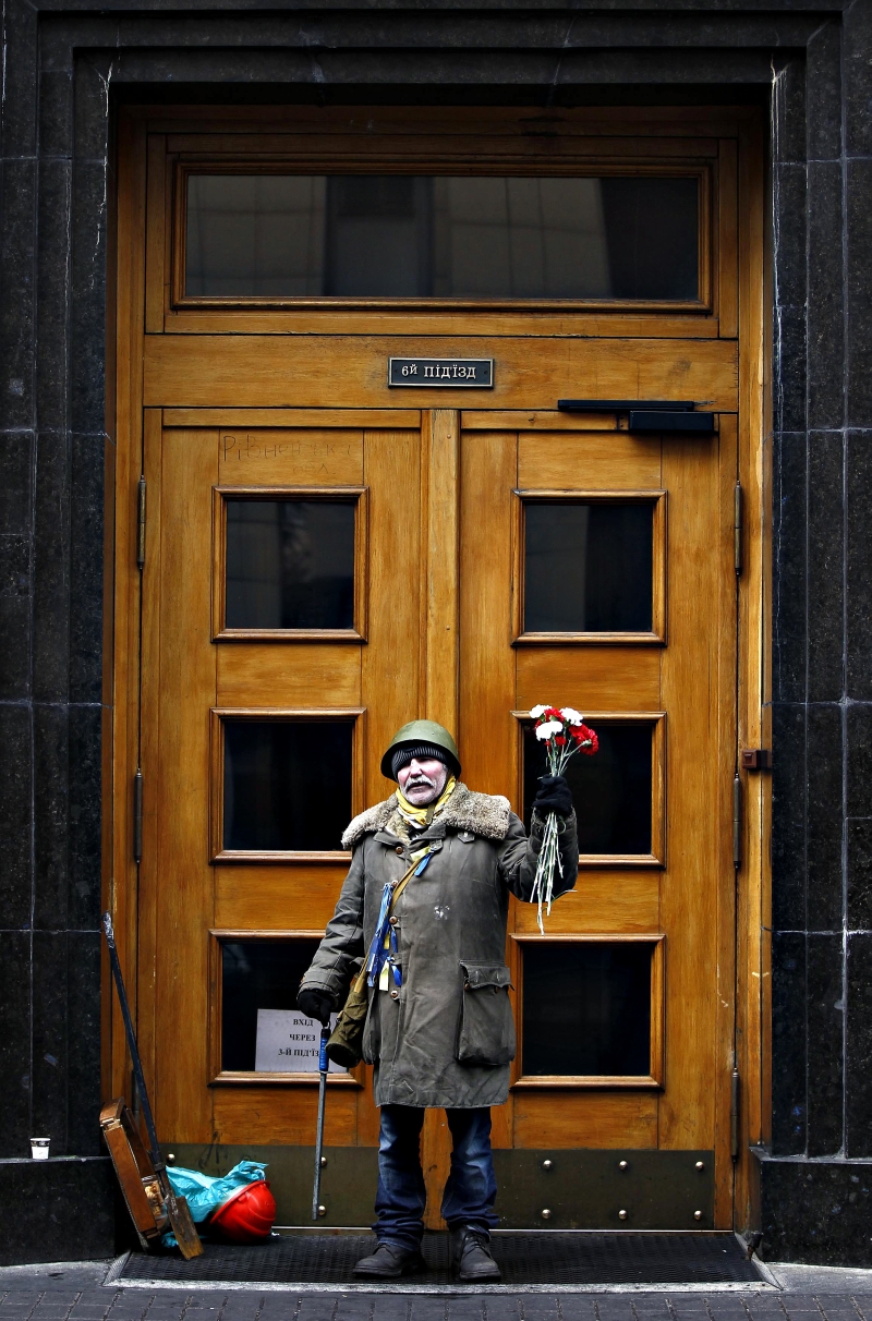 Ativista anti-Yanukovich segura flores enquanto faz a guarda de prédio público em Kiev | David Mdzinarishvili/Reuters