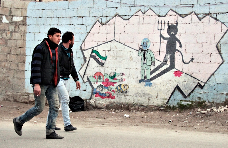 Moradores de Kafranbel, na província de Idlib, passam por mural do artista e ativista sírio Ahmad Jalal | Fadi Mashan/Reuters