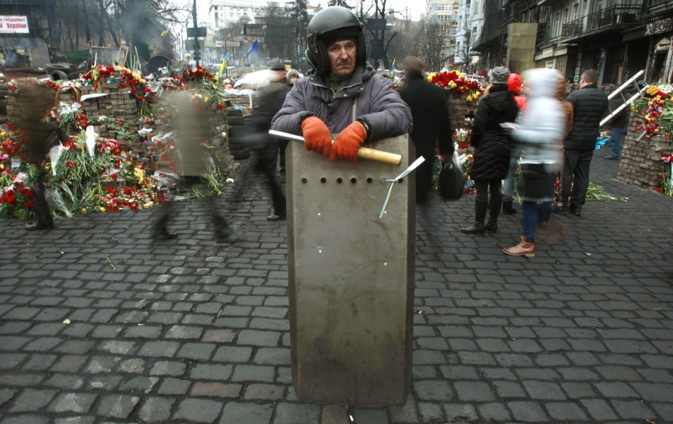 Manifestante "mantém" guarda em praça de Kiev, em meio a homenagens aos mortos durante os protestos | Reuters/David Mdzinarishvili