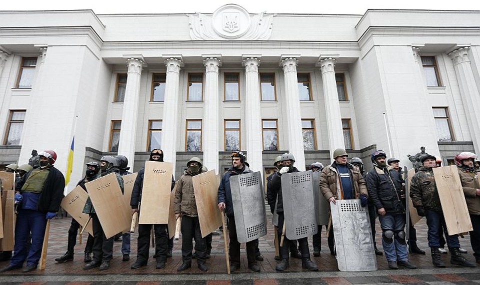 Protestantes antigoverno seguram escudos enquanto ficam de guarda em frente ao prédio do Parlamento Ucraniano em Kiev | REUTERS/Vasily Fedosenko