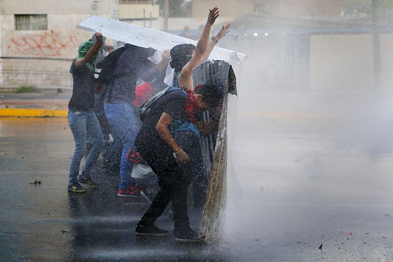 Manifestantes são atingidos por canhão de água durante confronto com a guarda nacional na Praça Altamira, em Caracas | REUTERS / Jorge Silva