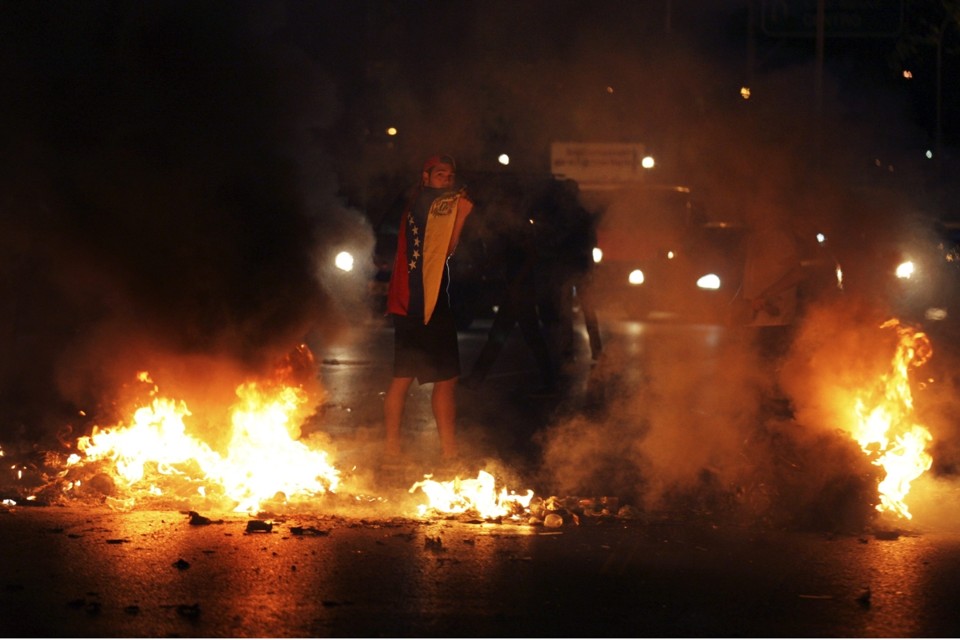 Manifestantes colocaram fogo em objetos para bloquear uma via expressa de Caracas na quinta-feira (13) | Reuters/Christian Veron