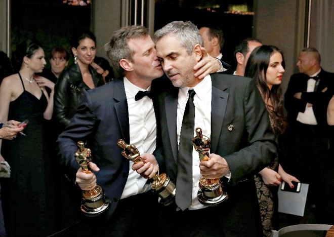 Spike Jonze (à esq.), vencedor do Oscar de melhor roteiro original por Ela, beija o cineasta Alfonso Cuarón, premiado pela direção de Gravidade: estatuetas mais que merecidas |