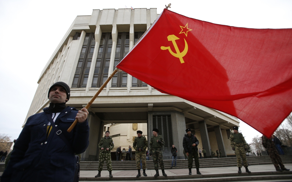 Homem segura bandeira que remete à extinta União Soviética durante protesto pró-Rússia em frente ao parlamento da Crimeia, em Simferopol | Reuters/David Mdzinarishvili