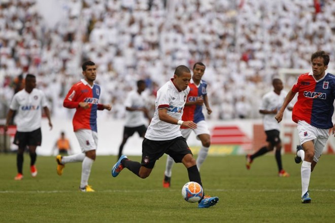 Marcos Guilherme carrega a bola entre a marcação paranista | 