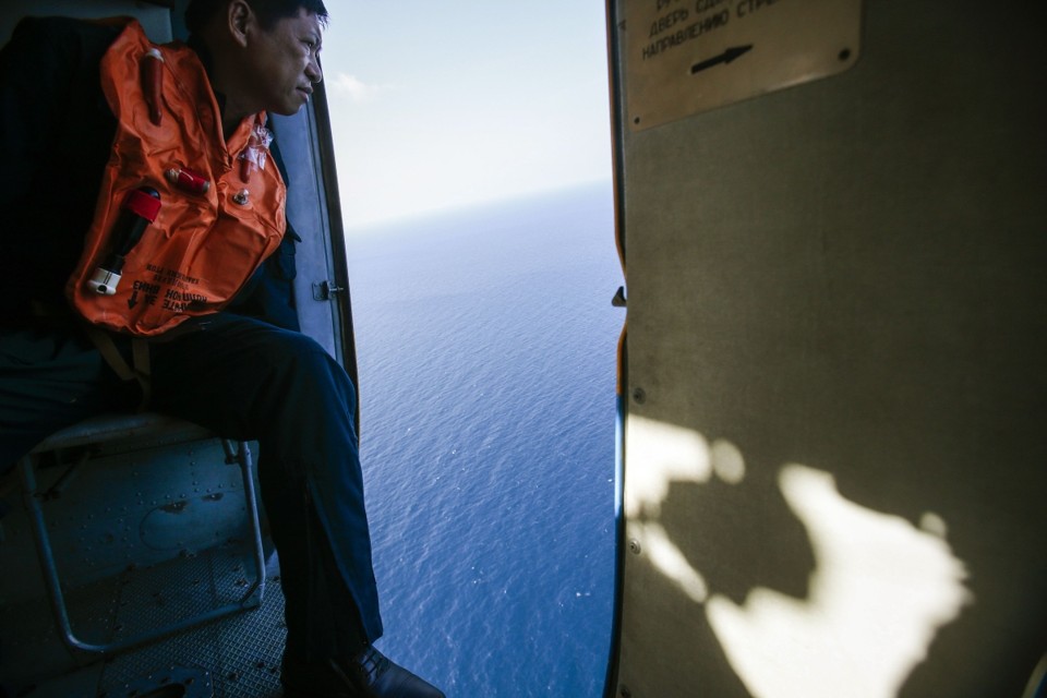 Homem olha pela janela de um dos helicópteros de busca procurando pelo avião que fazia o voo MH370 | Reuters/Athit Perawongmetha