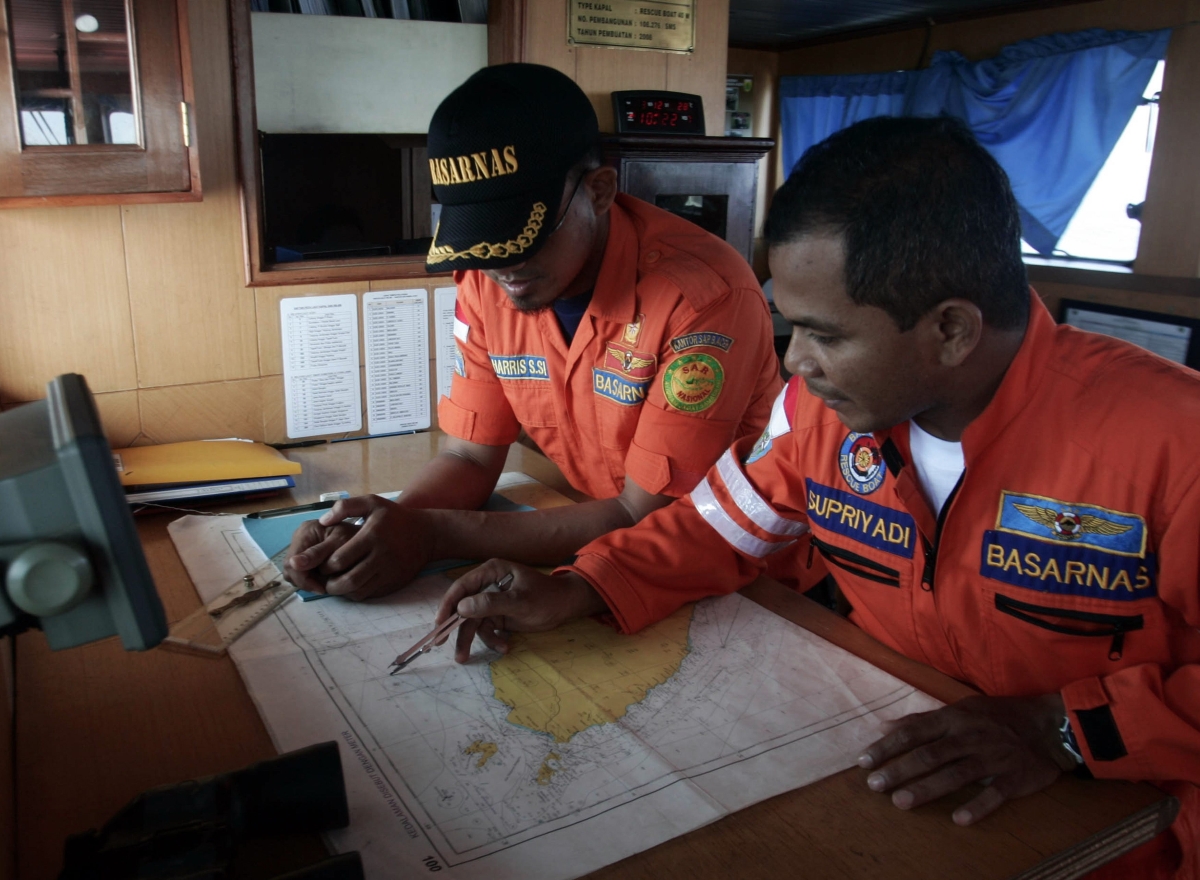 Homens das equipes de busca examinam os mapas do estreito de Malaca para orientar a procura pelo avião que fazia o voo MH370 | Reuters/Junaidi Hanafiah
