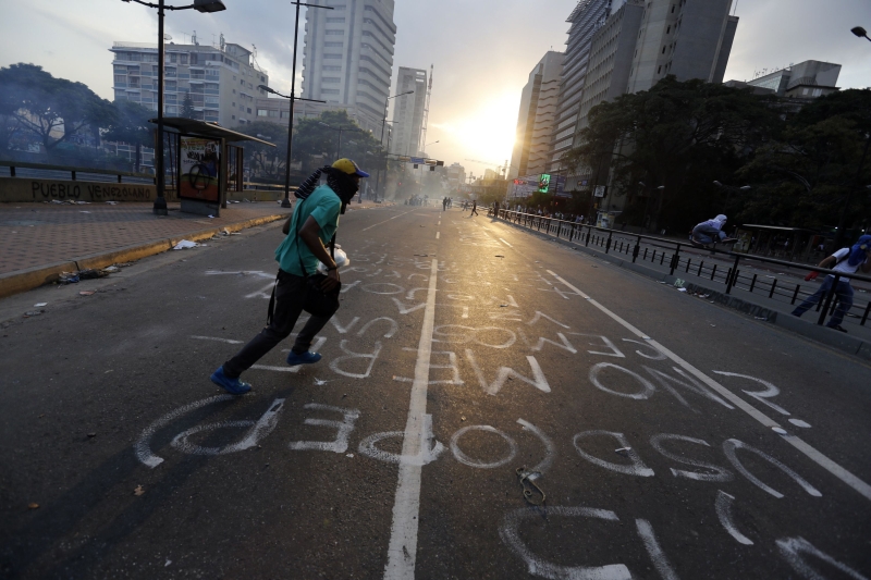 Manifestante antigoverno corre durante conflito com a polícia em rua de Caracas | Tomas Bravo/Reuters