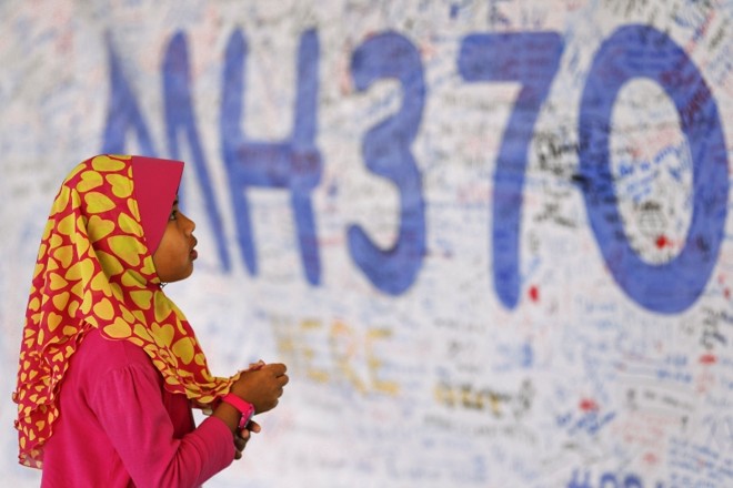Menina observa um mural de mensagens em homenagem aos passageiros do voo 370 da Malaysia Airlines no aeroporto de Kuala Lumpur | Damir Sagolj/Reuters