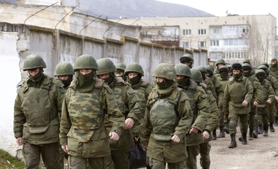 Homenns armados, provavelmente do Exército russo, caminham em uma base militar em Perevalnoye, próximo da Criméia | REUTERS/Vasily Fedosenko