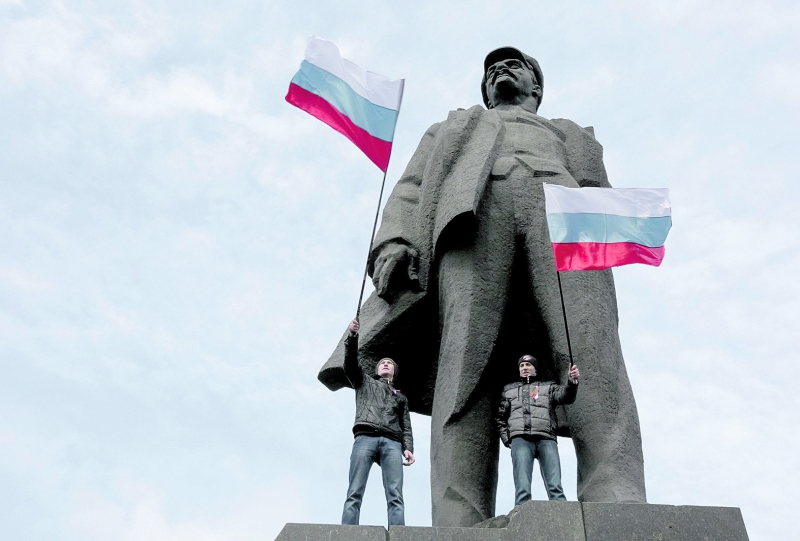 Ucranianos pró-Rússia se manifestam em cima da estátua de Vladimir Lenin, em Donetsk | Konstantin Chernichkin/Reuters