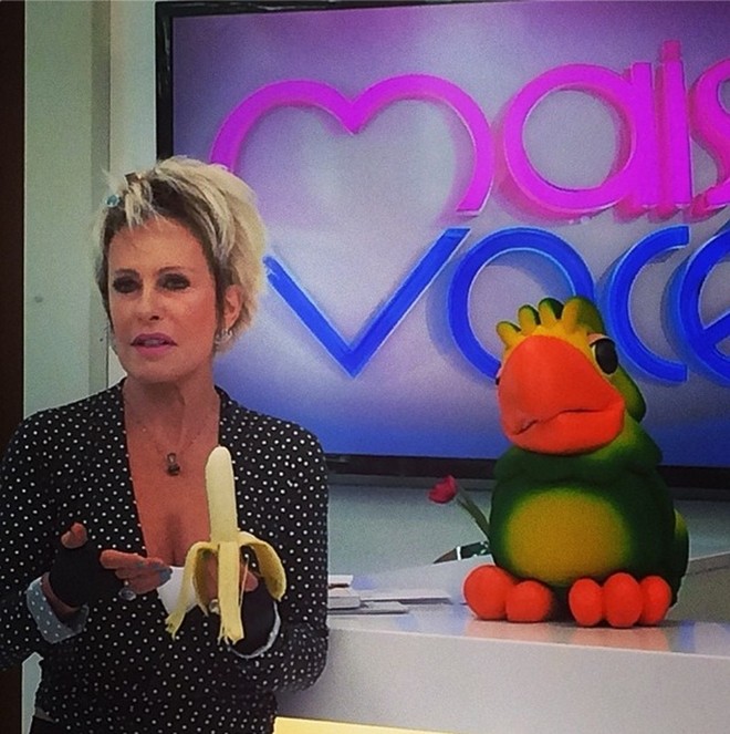 Apresentadora Ana Maria Braga come banana durante programa na televisão |