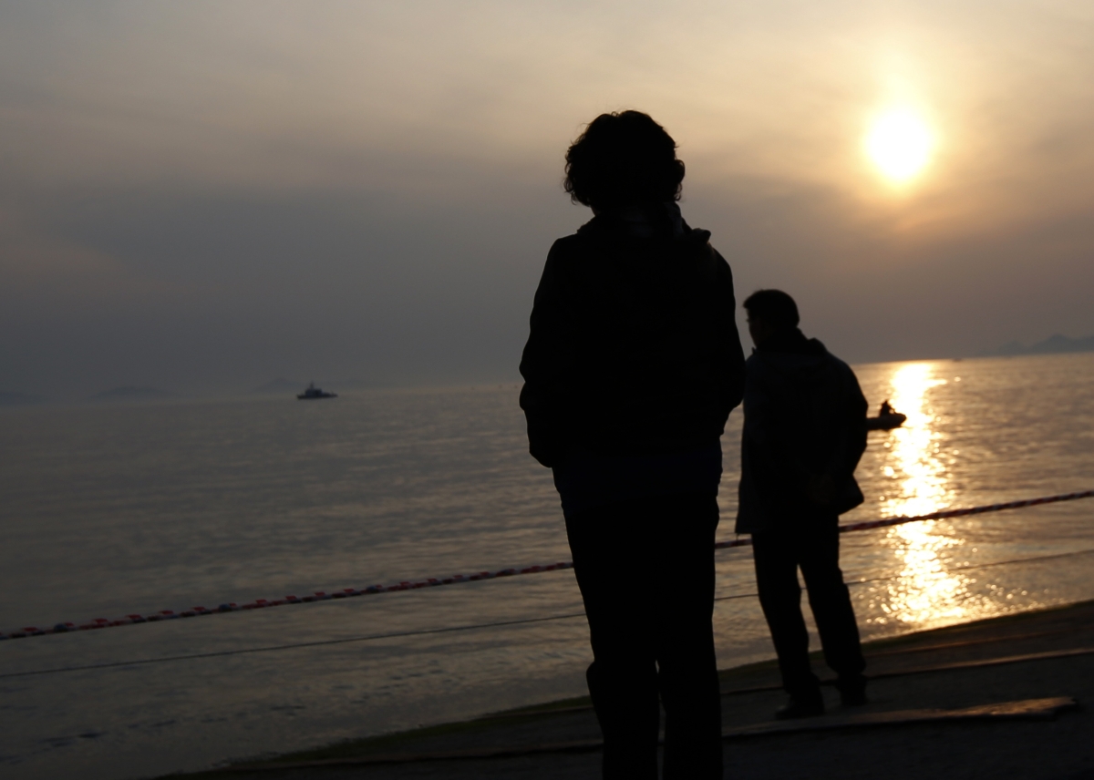 Familiares de passageiros da embarcação Sewol observam o mar à espera de notícias | Reuters/Issei Kato