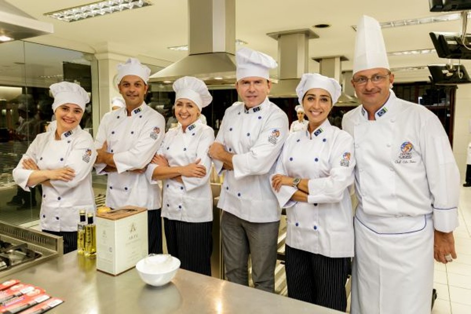 A jornalista Deise Campos, o restaurateur Marcelo Woellner Pereira, a blogueira de gastronomia Jussara Voss e a presidente da Paraná Turismo, Juliana Vosnika (a partir da esq.), com o presidente do Centro Europeu, Carlos Sandrini (calça cinza), e o chef Celso Freire na aula inaugural da primeira turma do curso de Chef Gourmet do Centro Europeu | Amarildo Henning