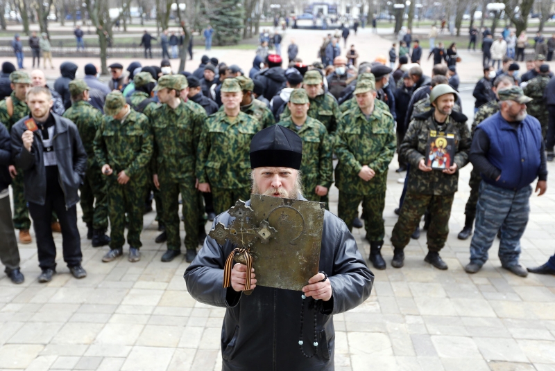 Homem com uma cruz na mão participa de manifestação pró-Rússia diante de prédio público em Lugansk, uma das cidades com prédios tomados por separatistas, no leste da Ucrânia | Shamil Zhumatov/Reuters