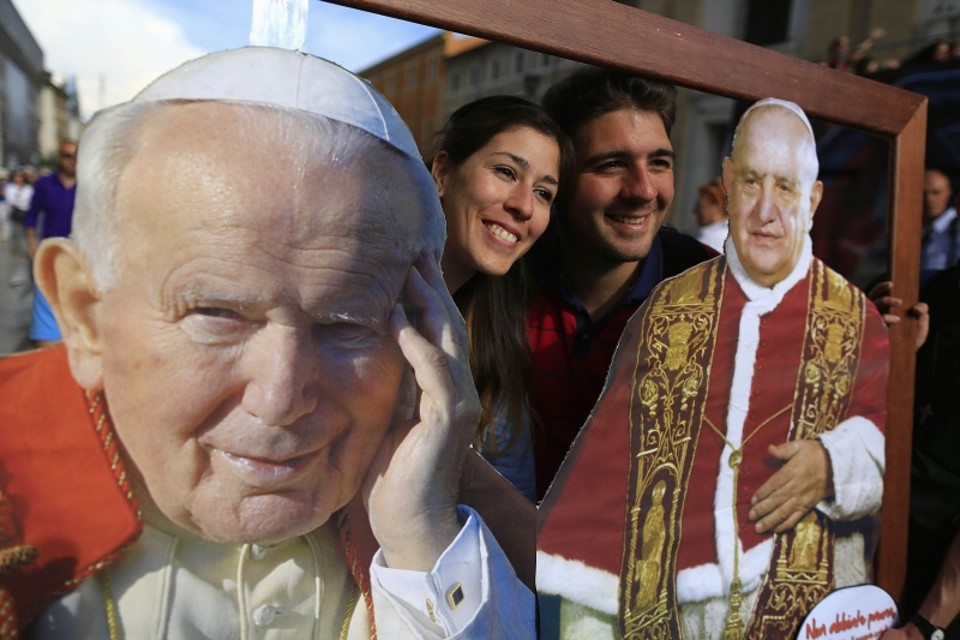 Fiéis fazem foto usando moldura com as imagens de João Paulo II e João XXIII, papas que serão santificados amanhã | Tony Gentile/Reuters