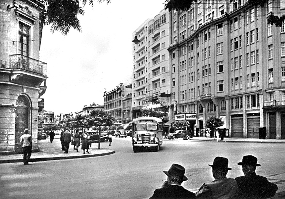 A Avenida Luiz Xavier sempre atraiu a atenção dos curitibanos, como é o caso dos cavalheiros da foto de 1940: sentados num banco da Praça Osório, apreciam o movimento | Acervo Cid Destefani
