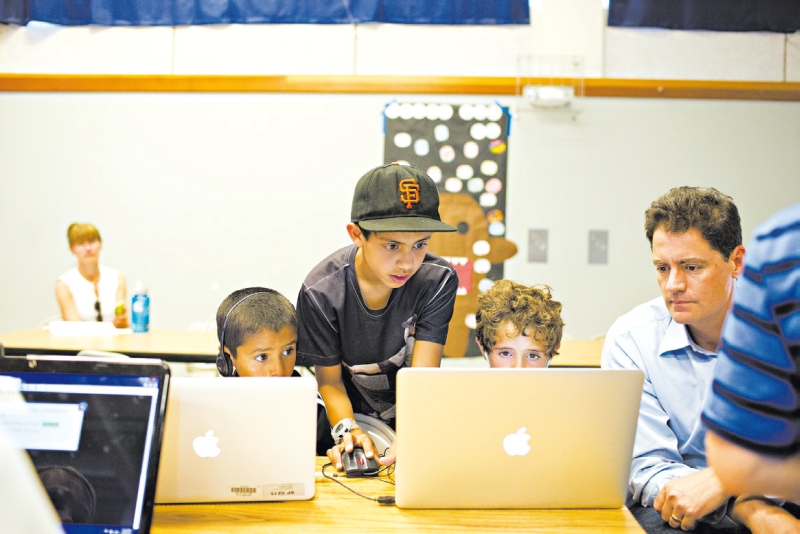 Imran Khaliq, 12, ajuda o irmão Farhan, 7, (e), e Aidan Brown, 6, em atividade | Jason Henry / The New York Times