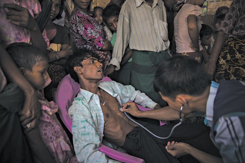 O número de casos encaminhados a hospitais caiu muito. Médico examina um homem Rohingya num campo de desabrigados | Fotos: Adam Dean para The New York Times