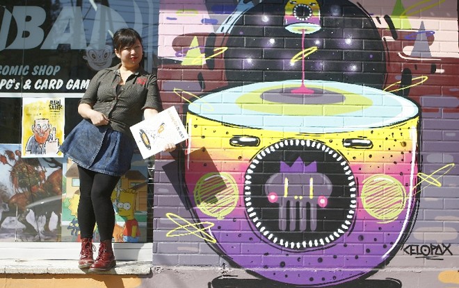 Mitie Taketani (e Allan Sieber, no cartaz) posam em frente à Itiban: paraíso das HQs |