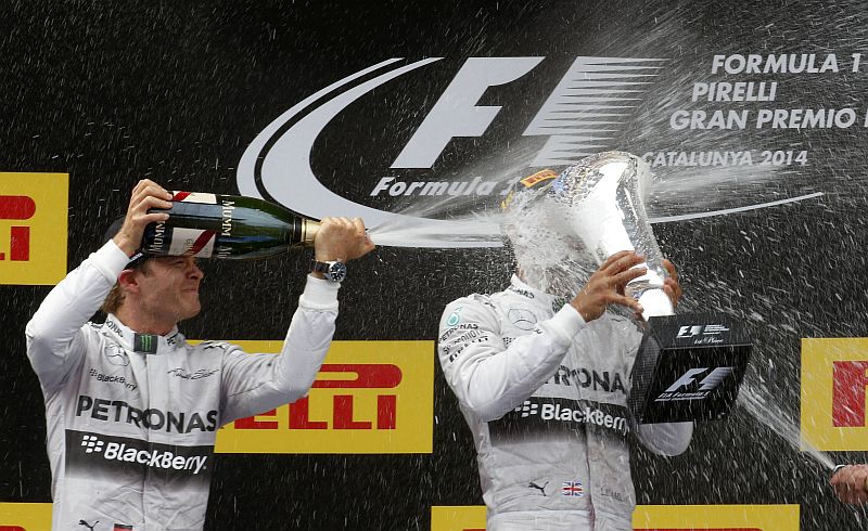 Lewis Hamilton recebe um banho de champanhe do companheiro de equipe, Nico Rosberg, no pódio do GP da Espanha, em Barcelona. O inglês venceu a quarta corrida seguida | REUTERS / Juan Medina