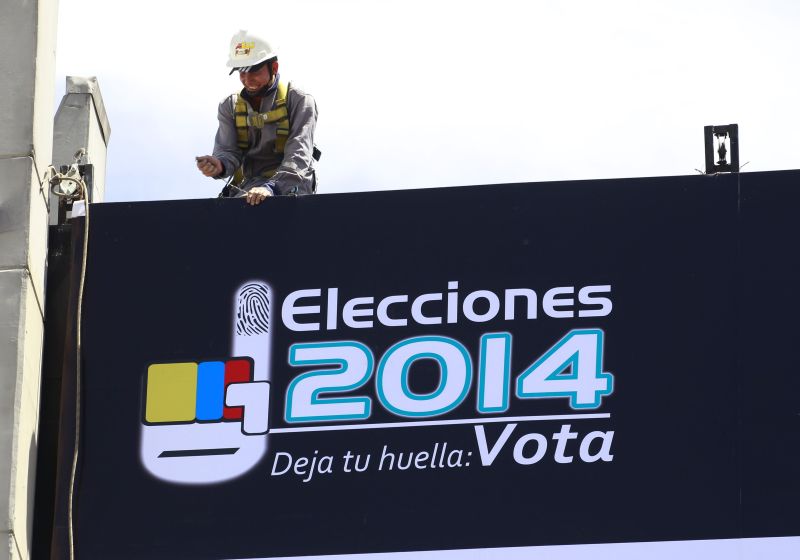 Homem coloca cartaz em frente ao maior colégio eleitoral da Colômbia, que elege novo presidente neste domingo (25) | REUTERS/Jose Miguel Gomez