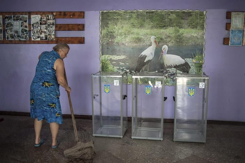 Mulher limpa sala onde haverá votação em Kiev, na Ucrânia | EFE / Roman Pilipey