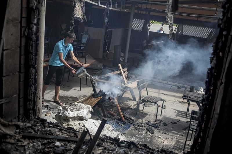Um homem tenta apagar o fogo de uma cafeteria destruída pelos confrontos desta madrugada | EFE/Roman Pilipey