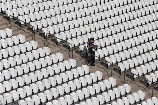 Voluntária verifica a numeração dos assentos do estádio. Capacidade do Itaquerão caiu de 68 mil para 61,2 mil lugares, para acomodar imprensa e câmeras de televisão. | 