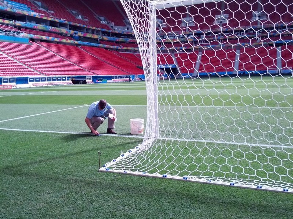 Funcionário da Fifa usa esponja para tirar os excessos de tinta das linhas do gramado. | André Gonçalves/ Gazeta do Povo
