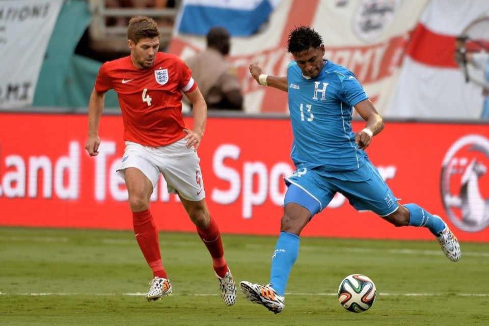 Hondurenho Carlos Costly chuta sob marcação do meia inglês Steven Gerrard | Steve Mitchell/USA Today
