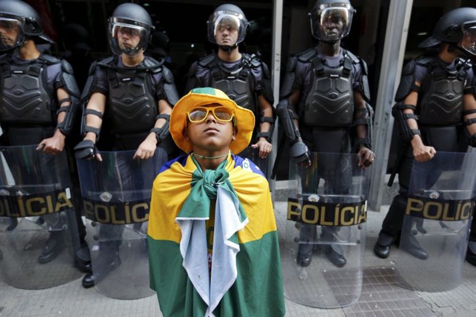 Garoto com a bandeira do Brasil á frete de policiais responsáveis pela segurança no metrô de São Paulo | Reuters