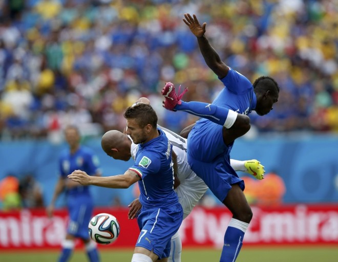Os italianos Ignazio Abate e Mario Balotelli (dir.) competem com o jogador uruguaio Egidio Arevalo Rios (centro) | 