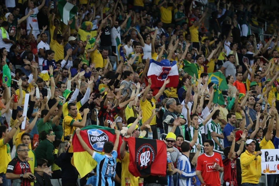 Em meio ao amarelo da seleção brasileira, bandeiras do Paraná e do Atlético e camisas do Coritiba na arquibancada suja de poeira da obra | Daniel Castellano / Agência de Notícias Gazeta do Povo