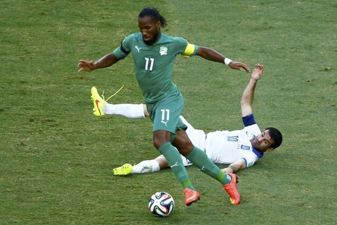 Drogba tem a posse de bola enquanto o grego Giorgos Karagounis cai no gramado | 