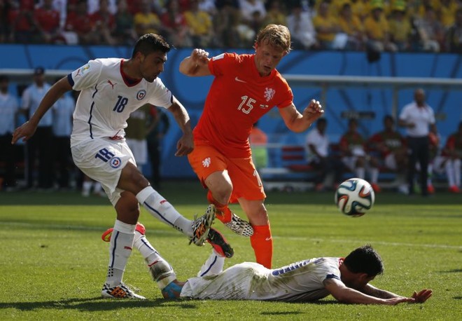 Gonzalo Jara (esq.), do Chile, briga pela bola com Dirk Kuyt (dir.), da seleção holandesa, enquanto o chileno Charles Aranguiz cai no gramado | 