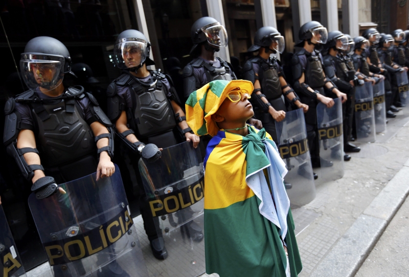 Policiais guardam a entrada de estação de metrô, com manifestante mirim fazendo pose logo à frente | Kai Pfaffenbach/ Reuters
