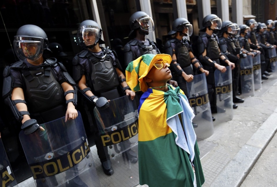 Policiais guardam a entrada de estação de metrô, com manifestante mirim fazendo pose logo à frente | Kai Pfaffenbach/ Reuters