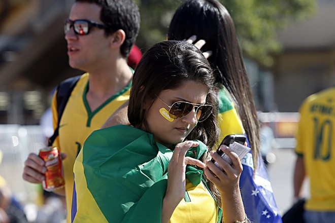 Torcedora brasileira observa o celular antes de entrar no estádio de São Paulo |